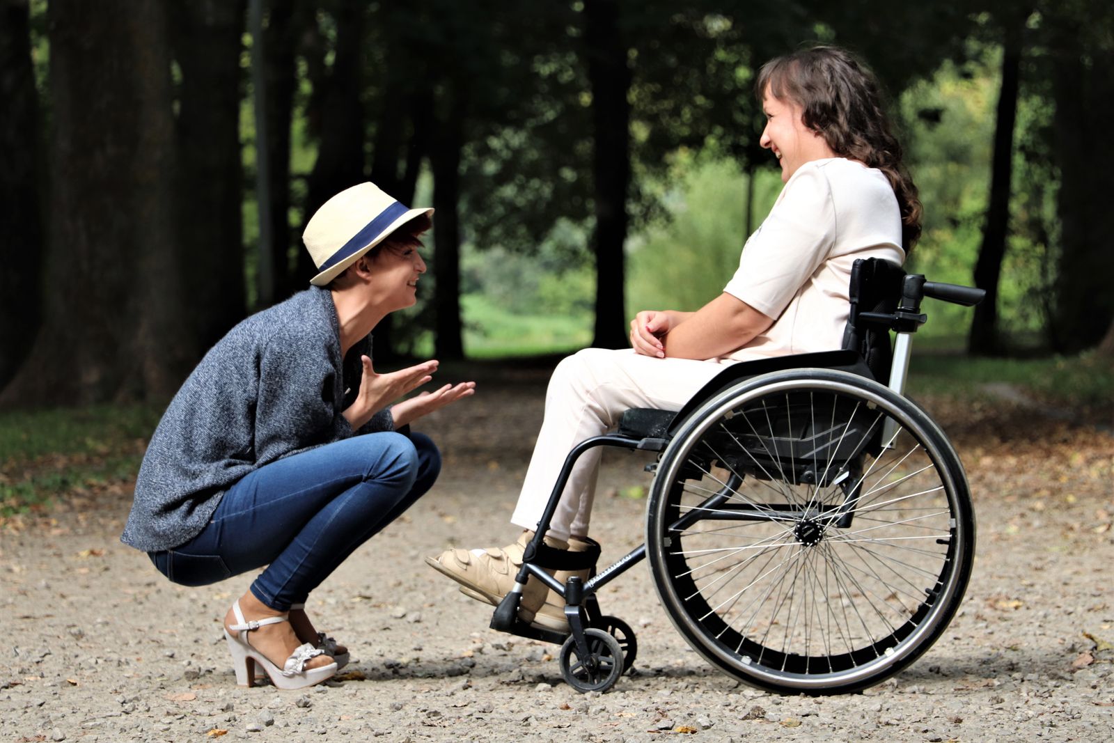 A support worker chatting happily with a man using a wheelchair in the park
